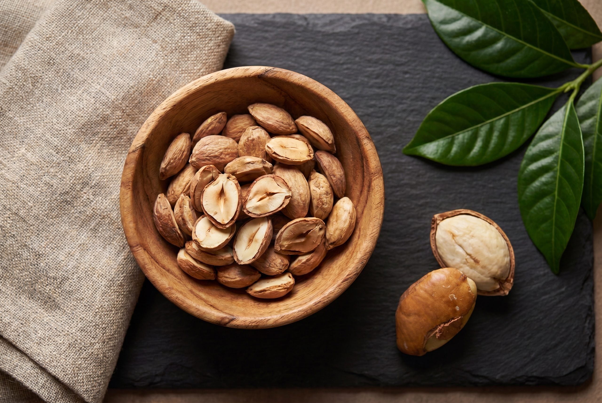 Dried African mango dika seed kernels of Irvingia gabonensis in a wooden bowl on dark slate