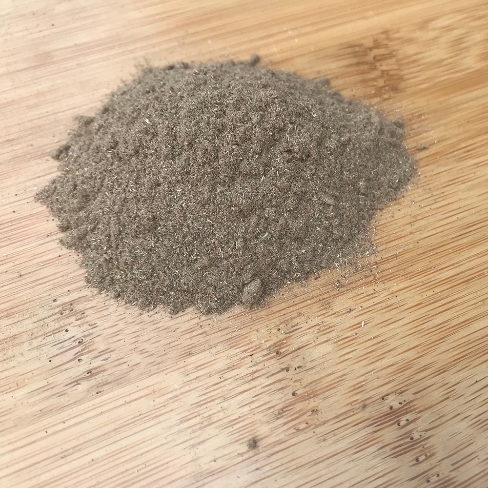 Healthy Blood Powder A close-up mound of the fine, herbal Healthy Blood Powder blend on a wooden surface, showing its natural texture and color.