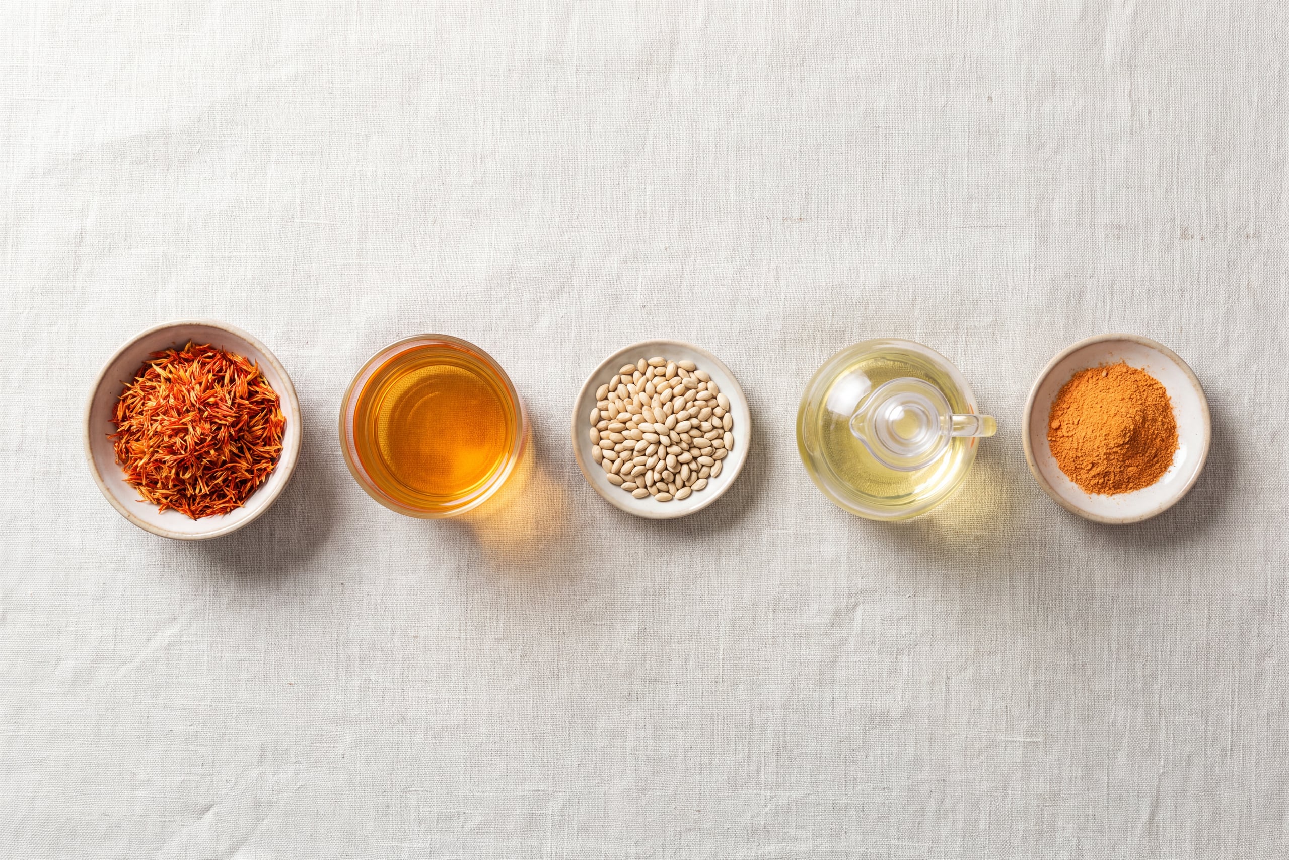 Safflower florets, tea, seeds, oil and petal powder in a row