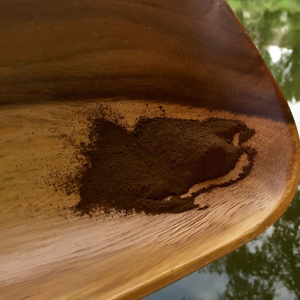 Restless (Sleeping Aid) Powder A close-up of the fine, dark texture of Restless Powder, an herbal sleep aid, resting on a natural wooden surface.