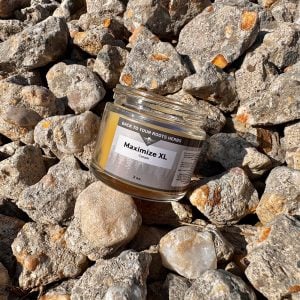 A jar of Maximize XL cream resting on a bed of rocks, symbolizing the strength and natural potency of this male enhancement formula.