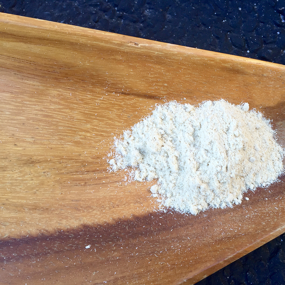 Astragalus Root Powder A pile of fine, light-colored organic astragalus root powder on a natural wood surface, ready for use as an herbal supplement.